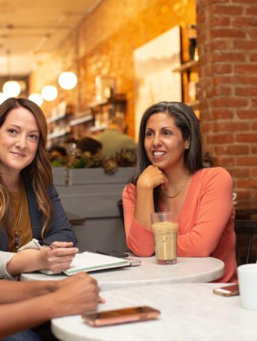 woman in black jacket sitting beside woman in white blazer